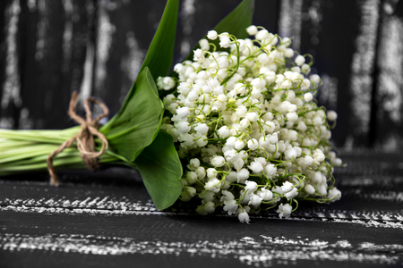 Lily of the valley on a dark wooden background. Lily of the valley bouquet. Space for text.の写真素材