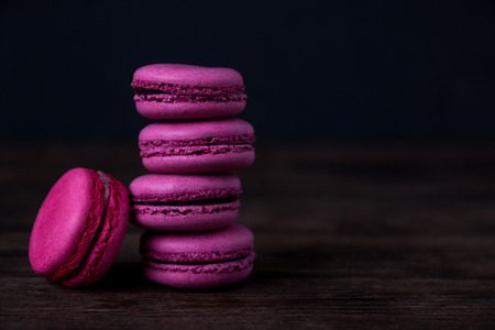 Pink macaroons with on dark wooden background. Berry macaroons on dark background. Macaroons close upの写真素材