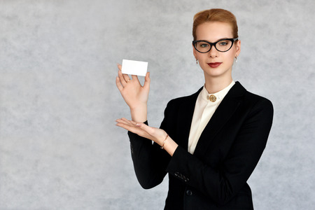 Young beautiful businesswoman showing white card with space for your textの写真素材