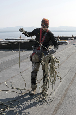 steeplejack testing his gear on the roof of the buildingの写真素材