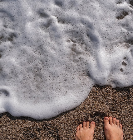 barefoot to the foaming wave of the sea. View from aboveの写真素材