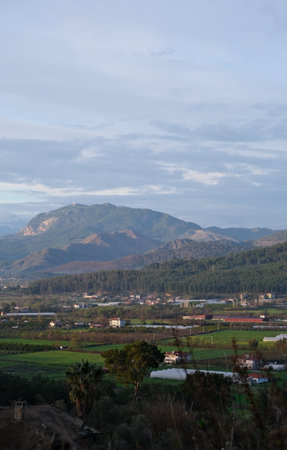 Vertical landscape of valley with mountain forest fields houses trees and clouds in turkeyの写真素材