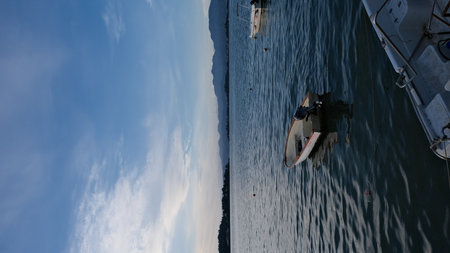 view on the sea and a boat with mountains and blue sky on the horizonの写真素材