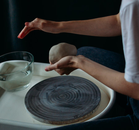 Close-up view of hands working on a potters wheel with a round piece of clayの写真素材