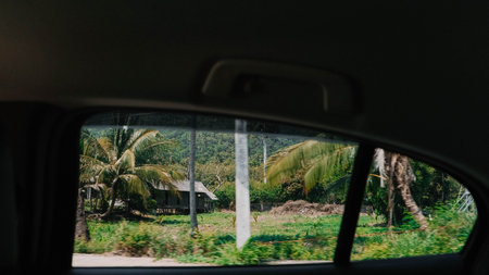 As I sit in the back seat of the car, I admire a breathtaking view of a lush, vibrant green field stretching out in front of meの写真素材