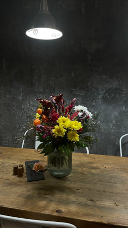 A beautifully vibrant bouquet arranged on a rustic wooden table, warmly lit, creates a cozy and inviting ambianceの写真素材