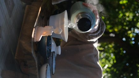 A captivating tea pouring ritual takes place in a lush outdoor setting, showcasing tranquility and peaceの写真素材