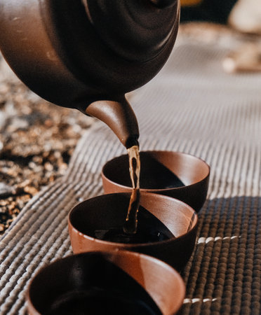 This is a serene moment that beautifully captures the tea being poured from a delicate teapot into three lovely cupsの写真素材