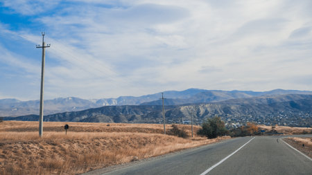 A tranquil road scene featuring mountains and clear skies, perfect for travel and nature-themed projects.の写真素材