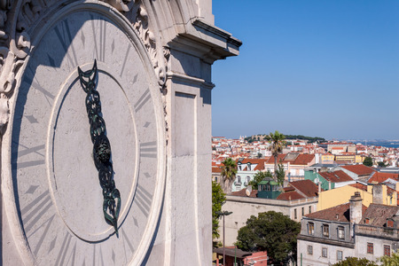 Close up of Gothic church tower clock with city views of Lisbon, Portugal in the back, on an sunny Summer afternoon. Concept for religion and Christianity/Catholicism.の写真素材
