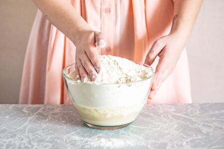 A woman mixes ingredients with her hands, the process of kneading the dough.