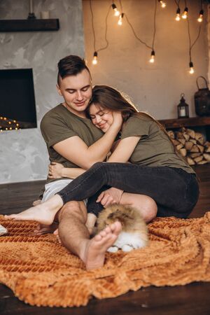 Beautiful happy man and woman in a sweet home with a catの写真素材