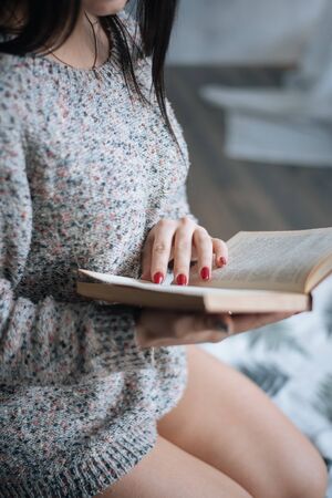 Relaxed happy woman reading a book in an ebook reader sitting on a floor at home
