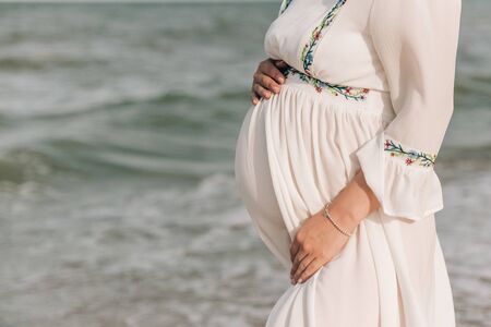 Happy Young Pregnant Woman on the Beach at the seaの写真素材