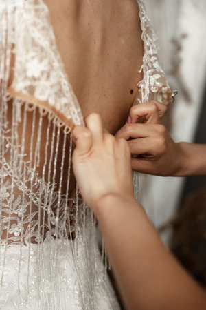 Beautiful bride in white dress near a mirror. Brides fees. Wedding. Happy bride preparing for her wedding. Happiest bridal day. Makeup and hairstyle in bride. Enjoy momentの写真素材
