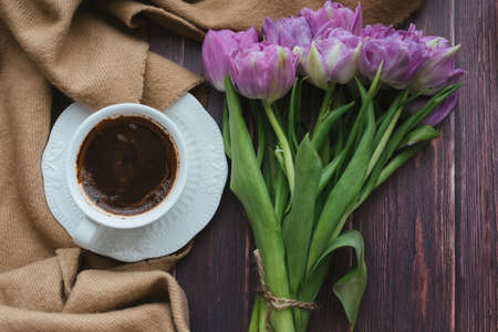 Spring flowers. Bouquet of tulips on a wooden background. Coffee and tulips. Flatley.の写真素材