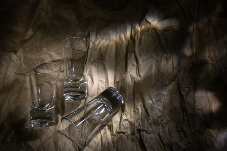 three glasses for vodka on the background of crumpled parchmentの写真素材