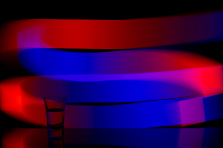glass of vodka on the background of the abstraction of colored stripesの写真素材