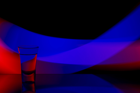 glass of vodka on the background of the abstraction of colored stripesの写真素材