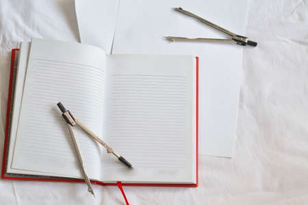 A compass lies on an open notebook. Set for work.