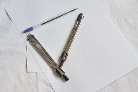 A compass and a pen lie on a piece of paper for work.の写真素材