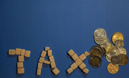 Wooden word TAX on blue surface with coins, close up viewの写真素材