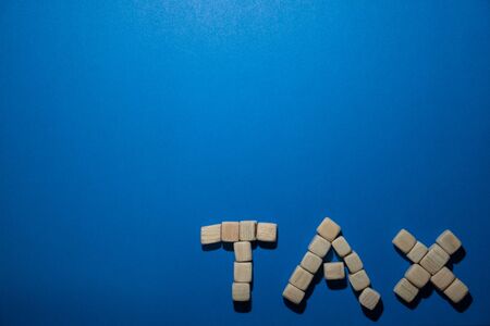 Wooden word TAX on blue surface, close up viewの写真素材