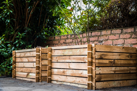 Two wooden compost bins in a back garden.