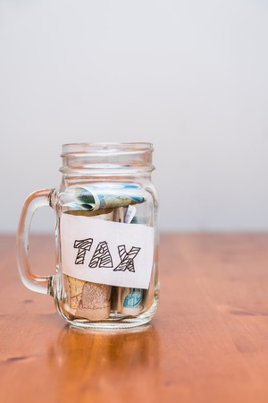 A jar labelled tax with currency notes insideの写真素材
