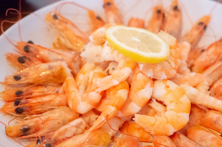 Fresh fried king prawns with sliced lemon on a plateの写真素材