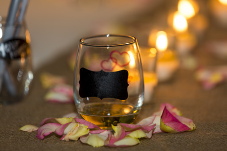 Burning candles at a wedding ceremony with a blank tag and hand drawn red hearts on a glass container with copy space for your message by romantic candlelightの写真素材