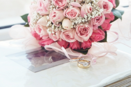 diamond ring, red and white gold ring and bouquet of roses on a wedding photo albumの写真素材