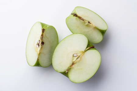 Sliced green apple half and two quarters on white background directly from aboveの写真素材
