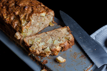 Sliced apple pie and kitchen knife grey pan holder on black from high angleの写真素材
