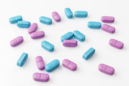 Mixed scattered pink and blue pills on white background from high angleの写真素材