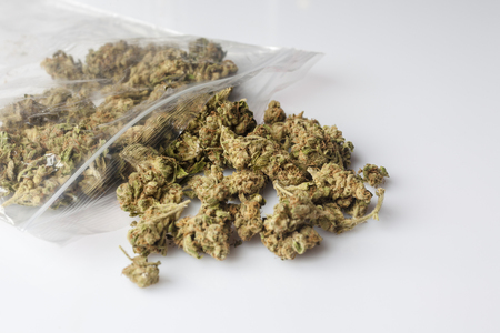 Pile of medical cannabis dried buds scattered from nylon package on white background from sideの写真素材