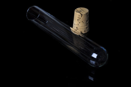 Empty glass transparent test tube diagonal with cork on side on black backgroundの写真素材