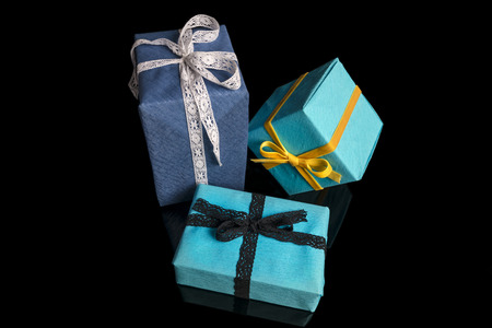 Three presents of different sizes wrapped in blue and turquoise textured paper tied with lace and...