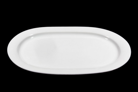 Flat white shallow porcelain oval plate with shoulders on black background from sideの写真素材