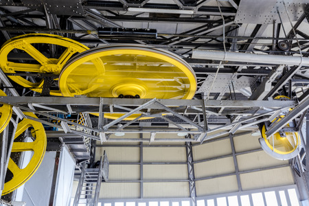 Yellow machinery wheels moving spinning with metal silver construction pieces and cables at Barcelonas port cable carの写真素材