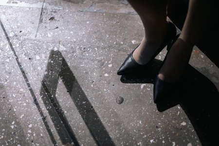 Female legs in black high heel shoes on the ground in the city.の写真素材