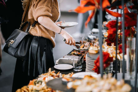 Catering service. A woman in a beige sweater holds a tray with food.の写真素材