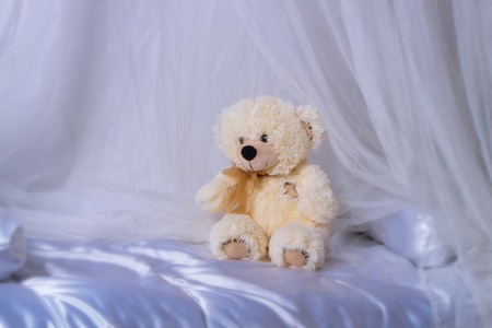 Single teddy bear sitting on the bedの写真素材