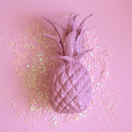Pink pineapple lying in party glitters. Concept minimal photo. Top view.の写真素材