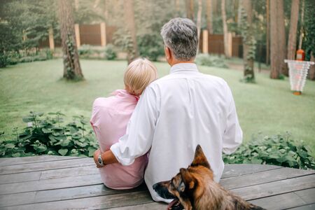 middle age couple sitting in their backyard together, rear viewの写真素材