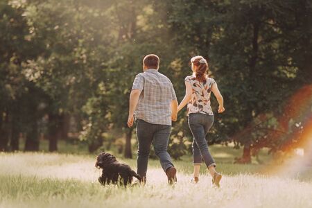 young couple running in the park with their dogの写真素材
