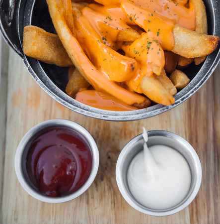French fries topped with cheese. Comprises sauce and mayonnaise on a wooden tray.の写真素材