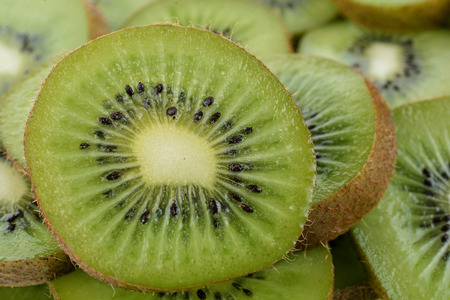 macro of a slice of green kiwi with white center and black seedsの写真素材