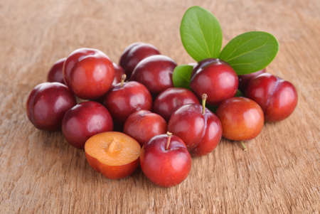Bright red plums on old wood backgroundの写真素材
