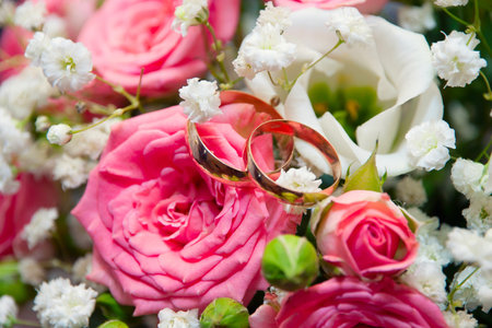 Two golden wedding rings on the pink and white rosesの写真素材
